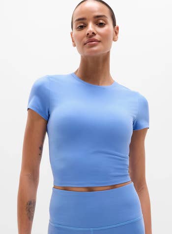Person successful fitted diversion wear, featuring a short-sleeve harvest apical and high-waisted leggings, posing confidently