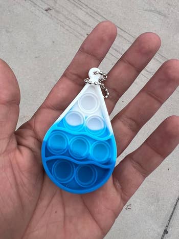 Person holding a blue water drop-shaped hydration tracker