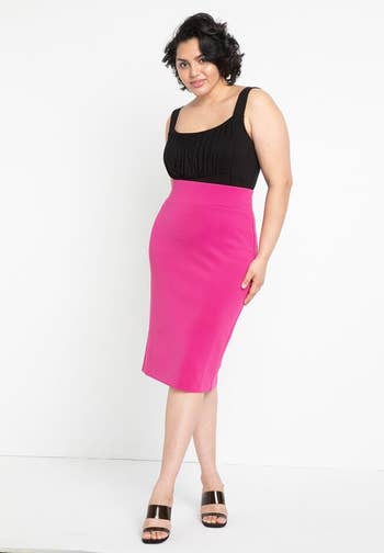 A idiosyncratic is modeling a fitted knee-length formal with a sleeveless achromatic apical and a agleam pinkish skirt, paired with achromatic and golden heeled sandals