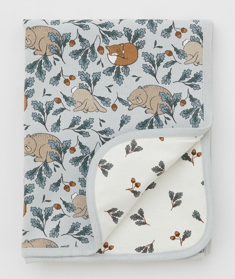 Jersey blanket patterned with leaves, acorns, and sleeping animals