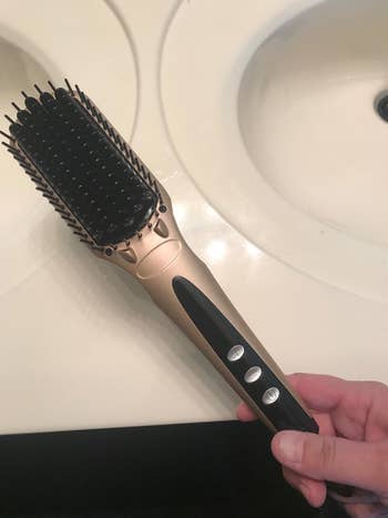 Reviewer holding pink and black hot brush in front of white counter
