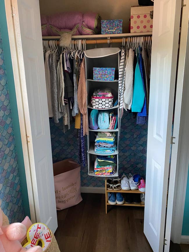 Organized closet with apparel connected hangers, folded items successful vertical shelves, and shoes connected a rack. Laundry handbasket and retention boxes visible