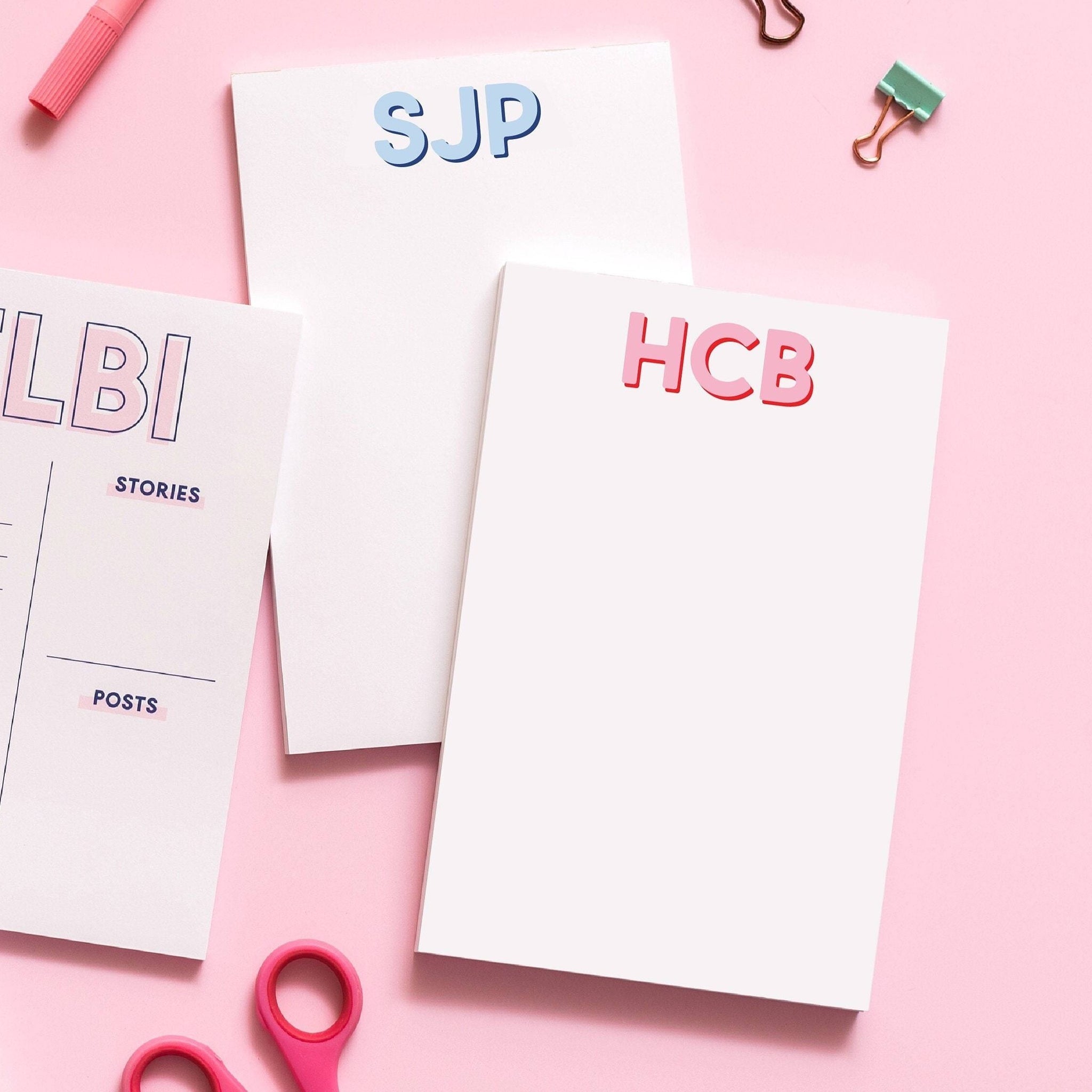 two monogrammed notepads, one with pink letters that read