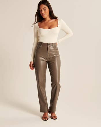 a model wearing taupe vegan leather pants with a white blouse