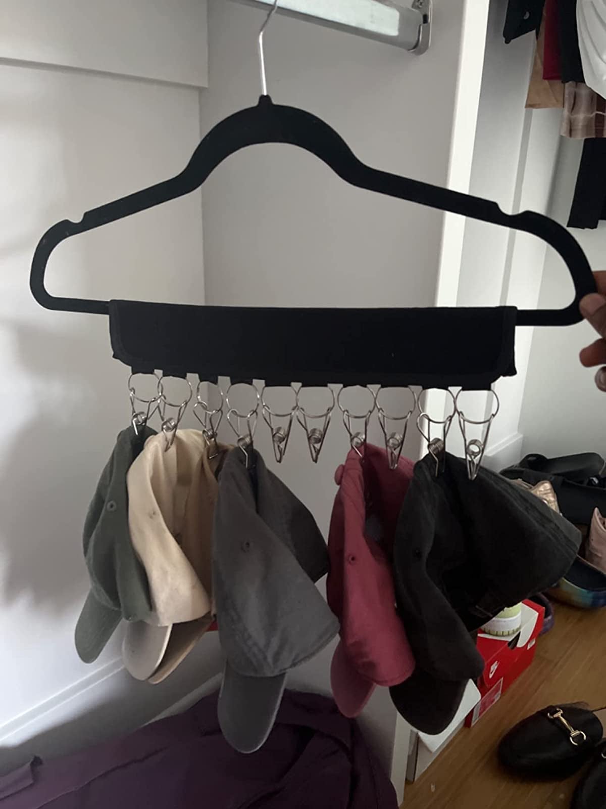 reviewer image of six caps hanging from the hanging cap rack
