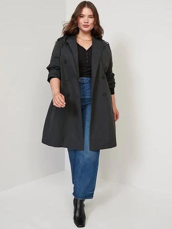 model wearing the black trench over a black top and jeans with black boots