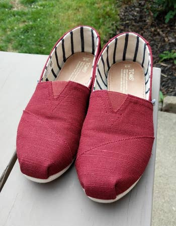 reviewer photo of their pair of red canvas slip-ons