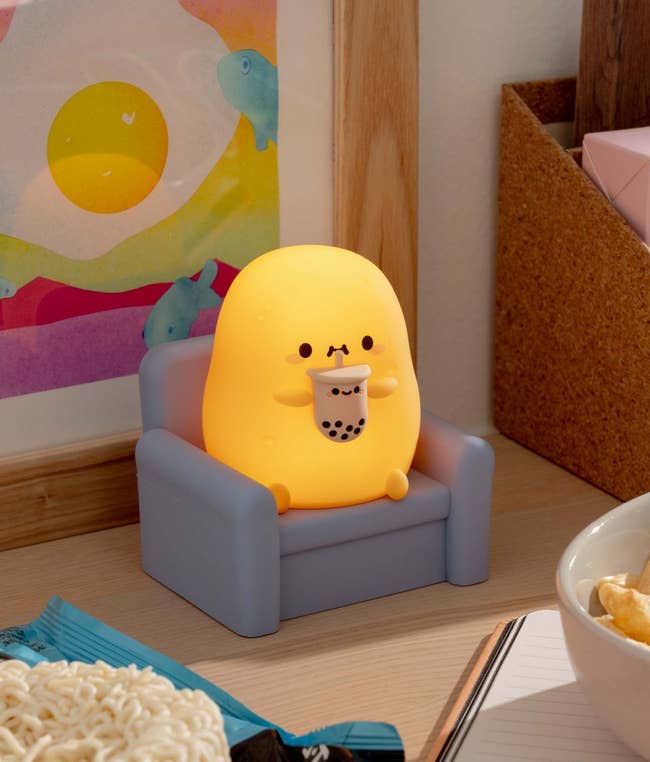 the lamp that looks like a potato in a chair drinking boba