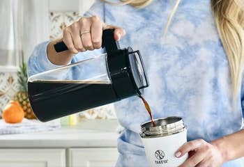 a model pouring coffee out of the pitcher into a tumbler
