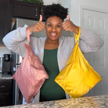 Person smiles, giving thumbs up   portion    holding reusable buying  bags successful  a room  setting