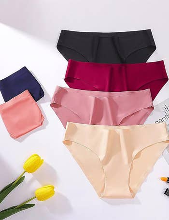 Five pairs of women's seamless underwear successful assorted styles are displayed with 2 tulips nearby