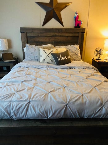 Reviewer image of front view of product in light gray on a wooden bed frame and star hanging above bed