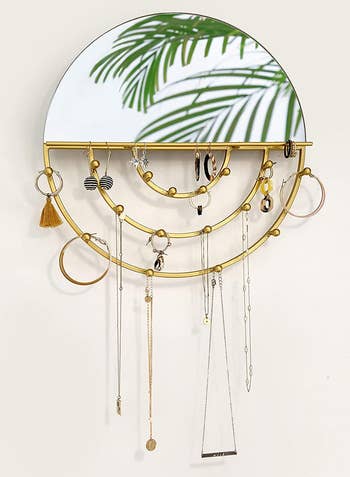 jewelry hanging from the round brass mirror