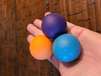 A reviewer holding the balls in purple, blue, and orange