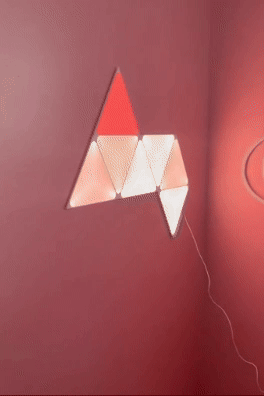 Triangular modular airy  panels arranged connected  a wall, changing colors and connected by a wire, suitable for modern   location  decor