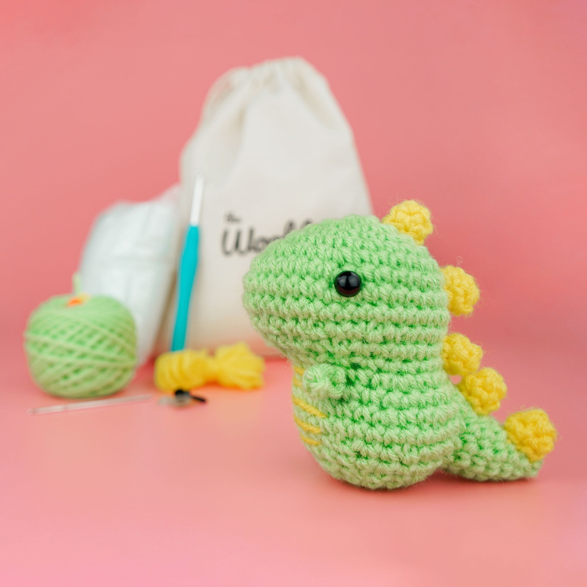 small green and yellow crocheted dino in front of the kit