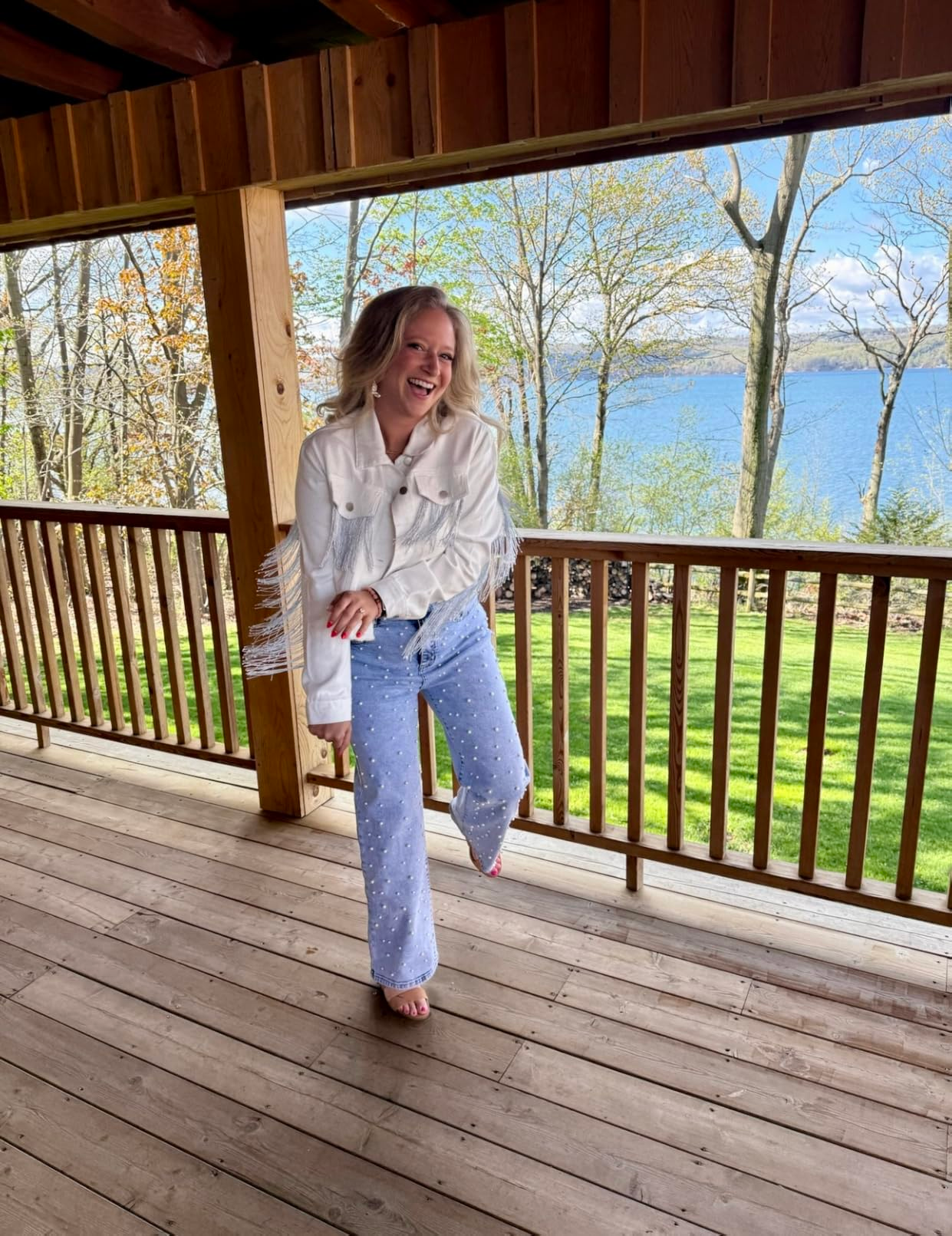 Person connected  a woody  platform  wearing a fringe overgarment   and pearl-studded jeans, with a scenic presumption    of trees and h2o  successful  the background