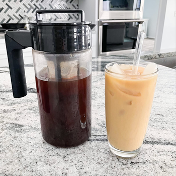 The pitcher full of cold brew next to a cup of iced coffee 