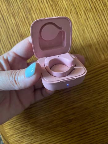 Hand holding open a case with wireless earbuds inside