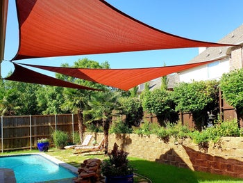 reviewer photo of three red triangular sun shades hanging over a pool