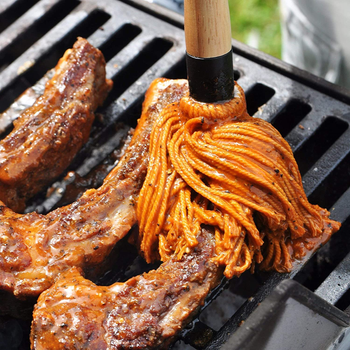 close up of the sauce covered basting mop spreading sauce on a rib