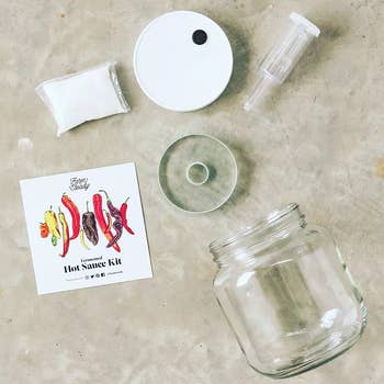 Hot sauce kit with a jar, funnel, lid, bag of salt, and recipe booklet on a light surface