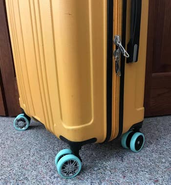 yellow suitcase with blue luggage wheel protectors