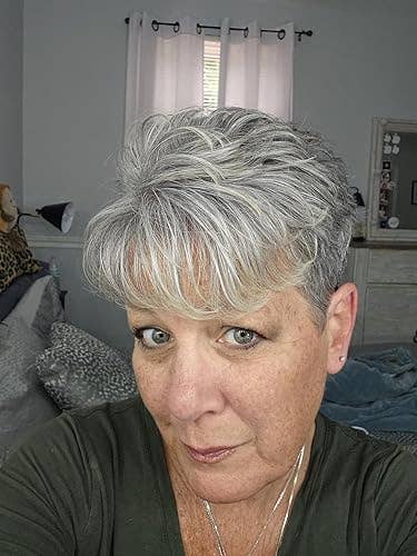 Person with short, layered grey  hairsbreadth  gazes astatine  the camera successful  a casual setting