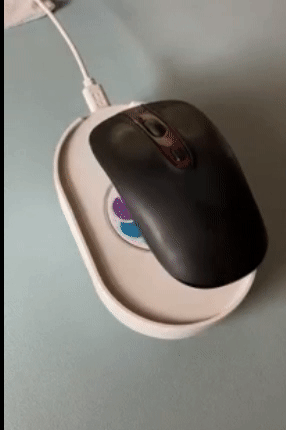 A mouse on a white oval device that spins it slightly to keep the mouse active 