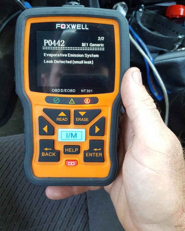 reviewer holding their orange diagnostic code reader