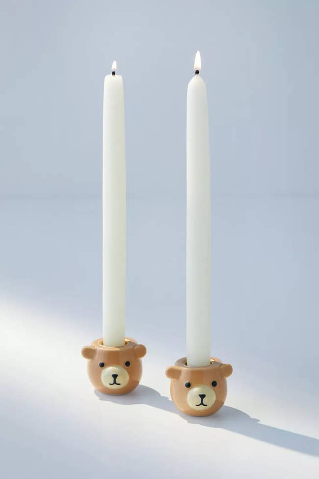 Two novelty bear-shaped candle holders with lit taper candles for home decor