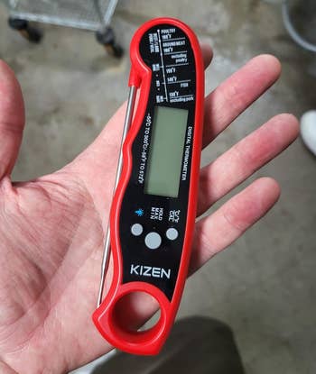 a reviewer holding the thermometer in red and black with the probe tucked in 