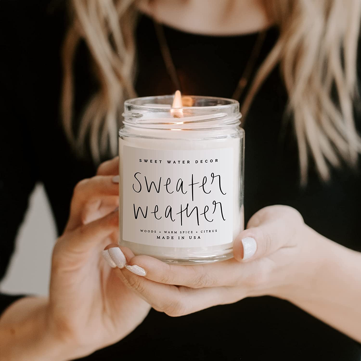 model holding the lit sweater weather candle