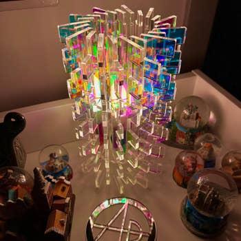 Intricate acrylic sculpture with geometric design, surrounded by assorted  collectible snowfall  globes connected  a show  shelf