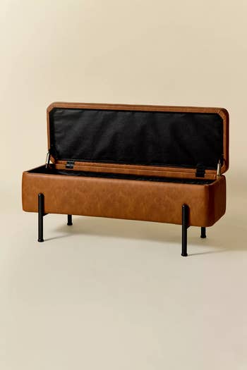 Open leather storage bench on black legs, showcasing interior space