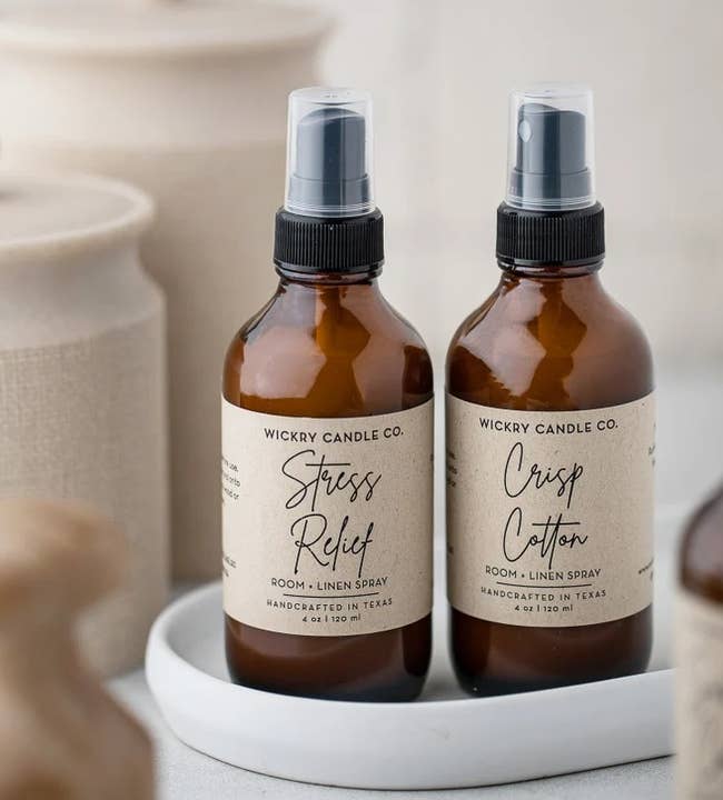 two amber spray bottles of the scented fabric freshener spray