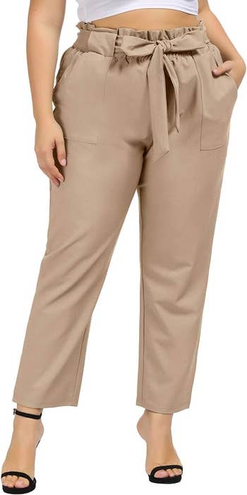 Model showcasing high-waisted paperbag trousers with a tie waist and ankle-length cut. Perfect for a stylish office look