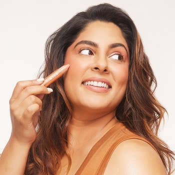 model applying the huestick to their face