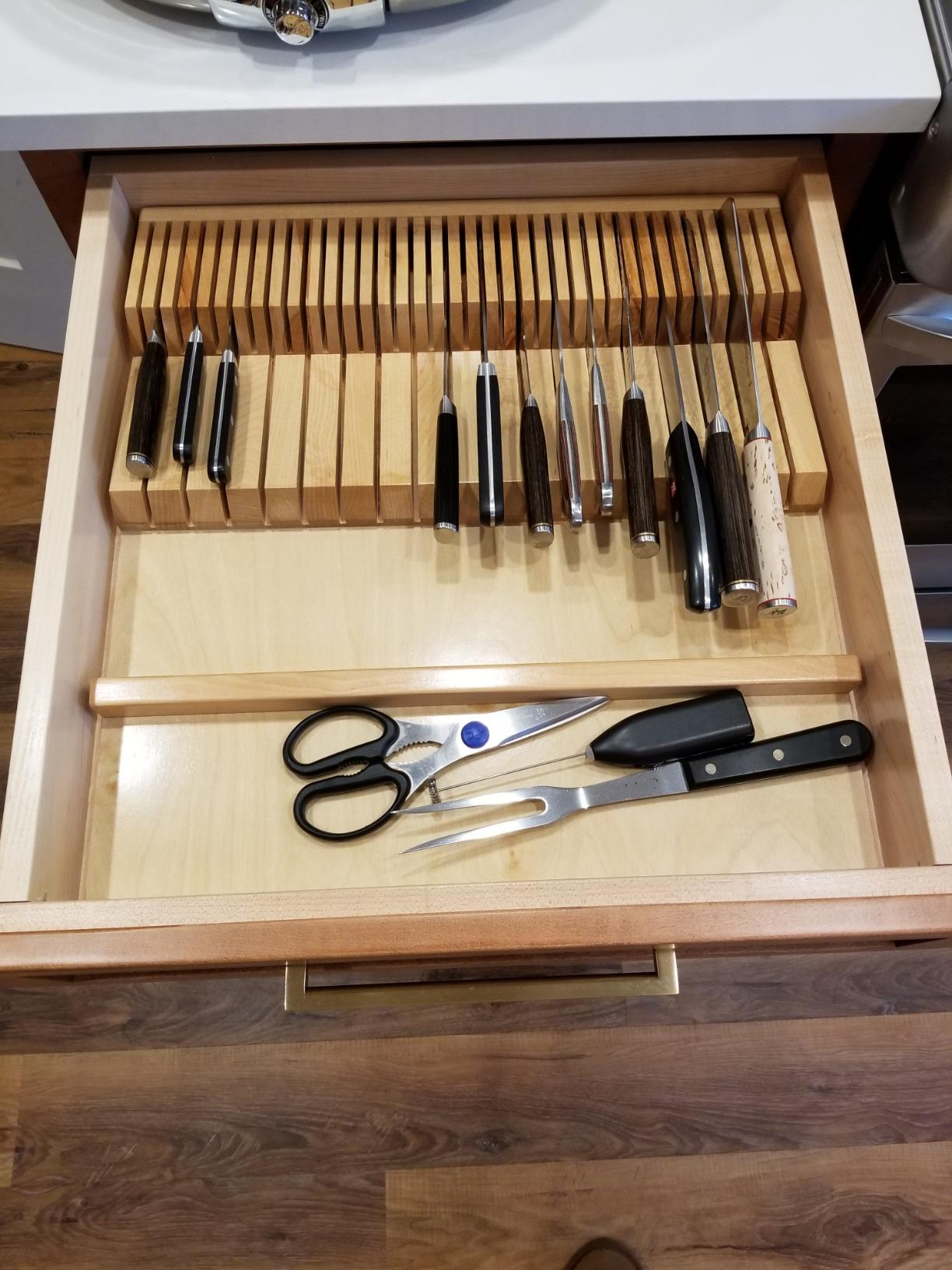 Wooden drawer organizer with various knives, kitchen shears, and utensils neatly arranged, highlighting efficient kitchen storage solutions