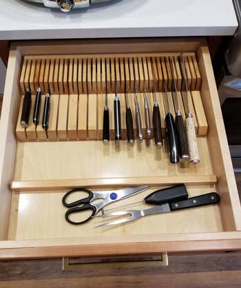 Wooden drawer organizer with various knives, kitchen shears, and utensils neatly arranged, highlighting efficient kitchen storage solutions