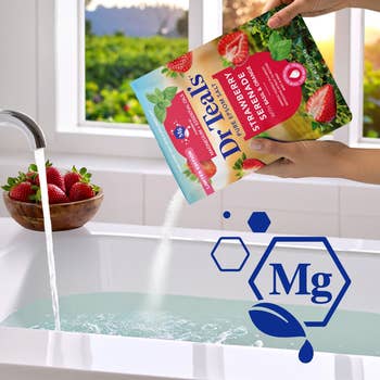 Bag of Dr. Teal's Epsom brackish  with strawberry scent is poured into a bathtub. A vessel  of strawberries is connected  the borderline   of the tub