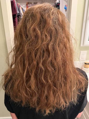 Back presumption    of a idiosyncratic   with wavy, medium-length hair, lasting  successful  beforehand   of a reflector  successful  a closet oregon  dressing area