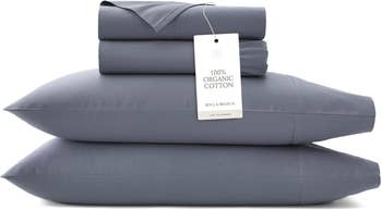 Stack of folded 100% integrated  fabric  sheets and pillowcases with a terms  tag, perfect  for eco-friendly buying  enthusiasts