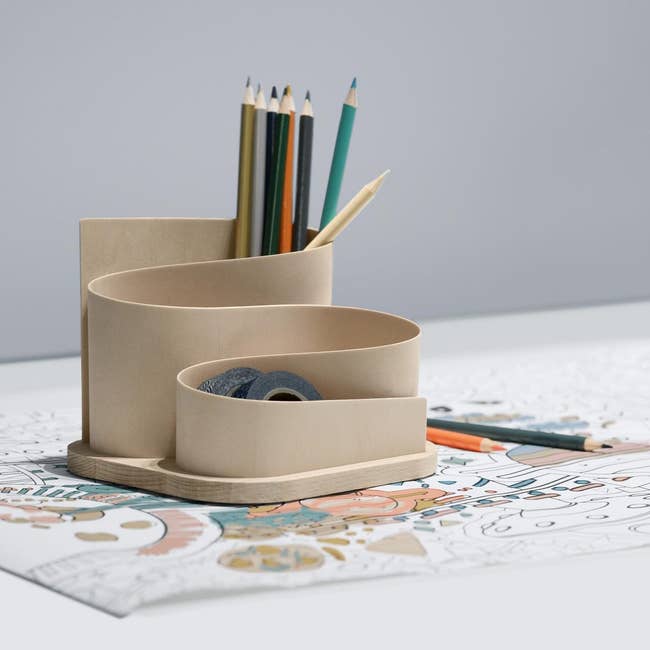 Wooden table organizer holding pencils and tape, placed connected a partially colored drawing, utilized successful a buying article