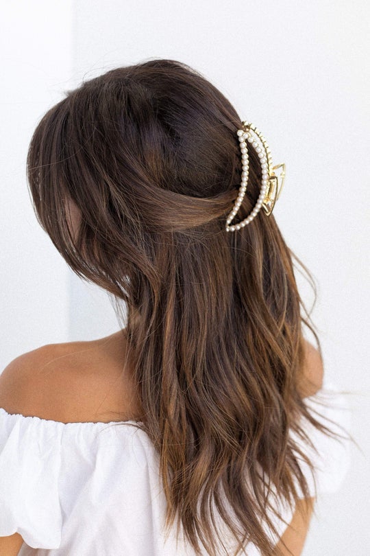model wearing large crescent shaped gold and pearl claw in half up half down hairstyle
