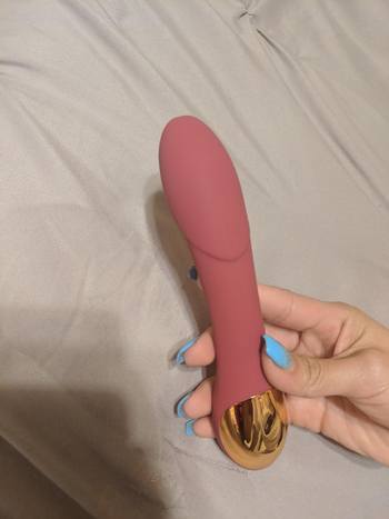 Hand holding pink and gold vibrator