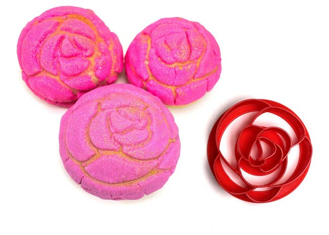 three conchas with pink sugar on top in the shape of a rose next to a rose shaped stamp