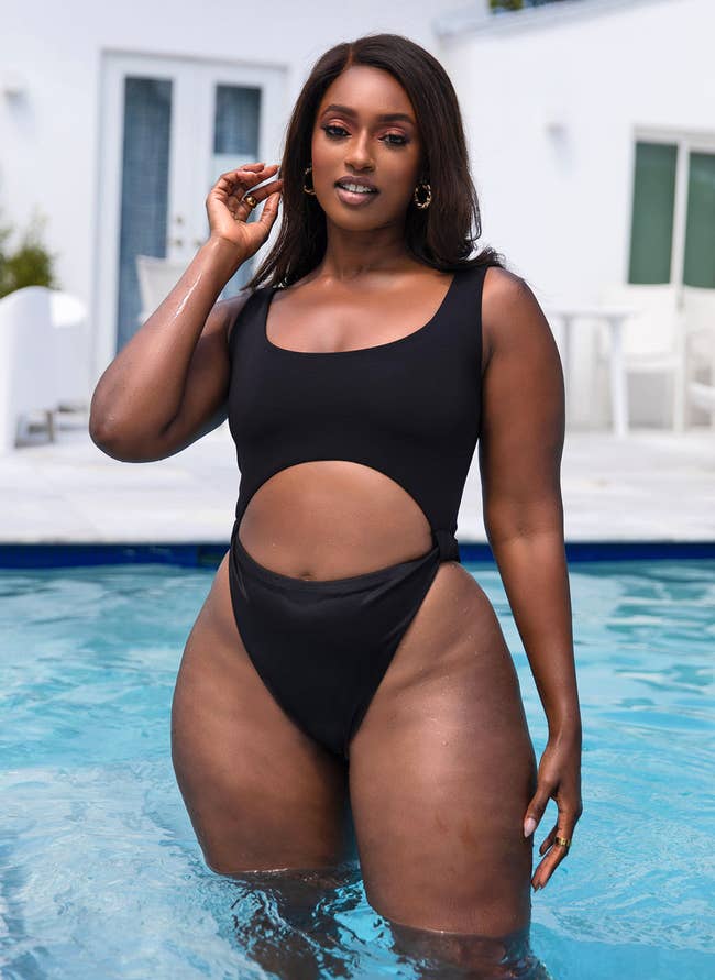 model posing in black cut out swimsuit in a pool
