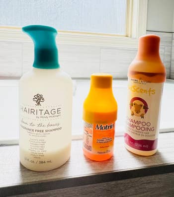 reviewer's three bottles on a windowsill with the colorful silicone covers on them 