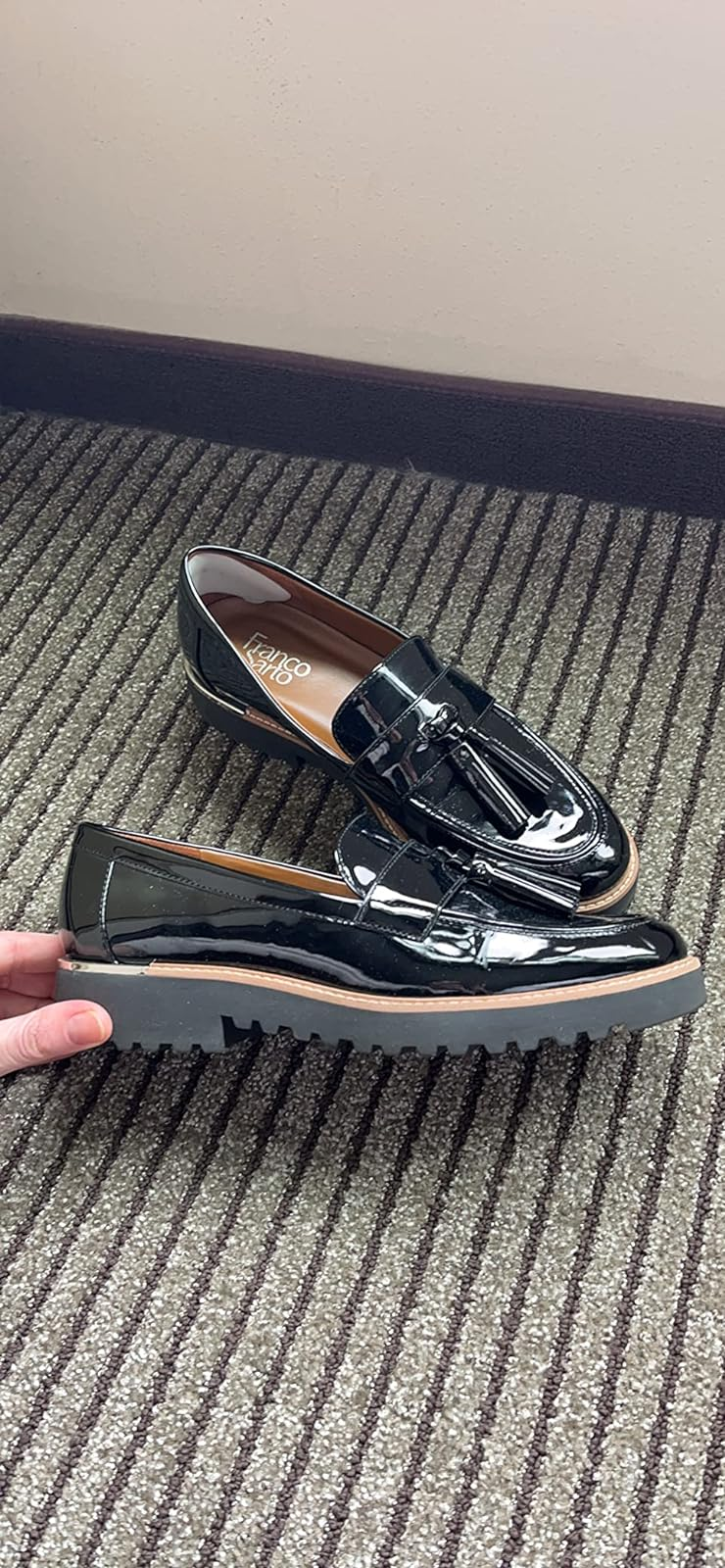A brace  of shiny achromatic  loafers with tassels